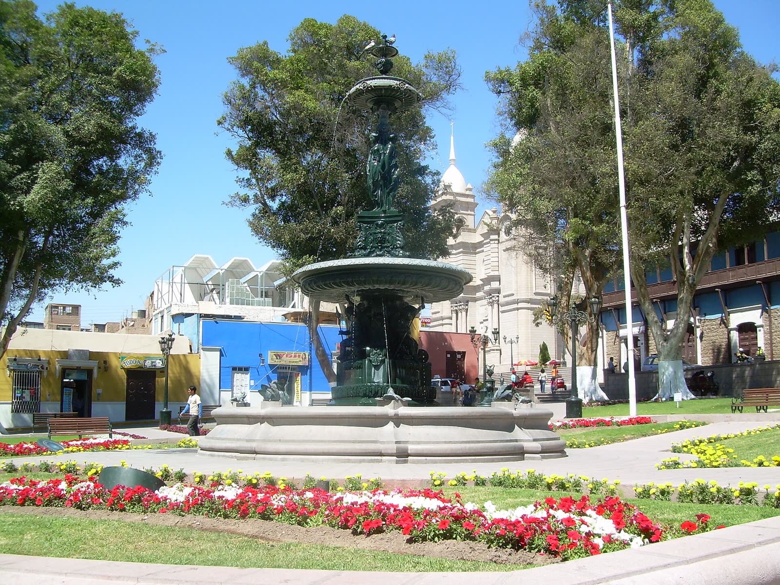 Pileta de hierro de la Plaza de Armas de Moquegua rodeada de flores rojas y blancas