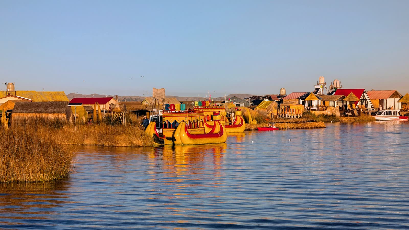 Balsas de totora frente a las islas flotantes de los uros, en el lago Titicaca, al atardecer